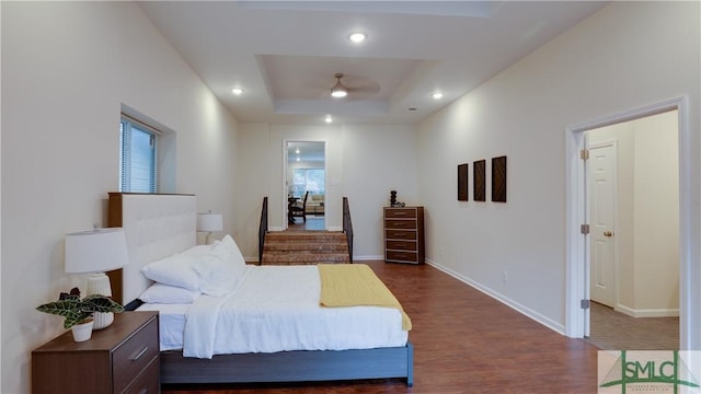 bedroom featuring baseboards, a tray ceiling, dark wood-style flooring, and recessed lighting