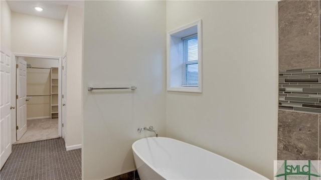 full bathroom with a spacious closet, baseboards, and a freestanding bath