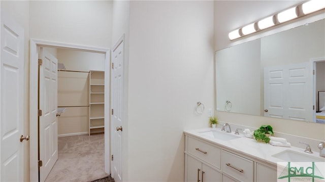 full bathroom featuring double vanity, a walk in closet, and a sink