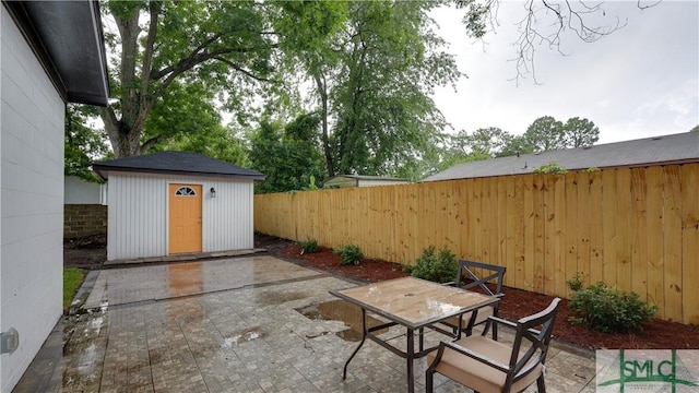 view of patio featuring a storage unit, outdoor dining area, an outdoor structure, and a fenced backyard