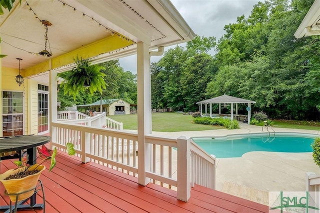 view of pool with a gazebo, a yard, a deck, and an outdoor structure