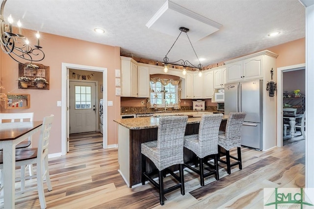 kitchen with a center island, light stone countertops, a textured ceiling, a notable chandelier, and stainless steel appliances