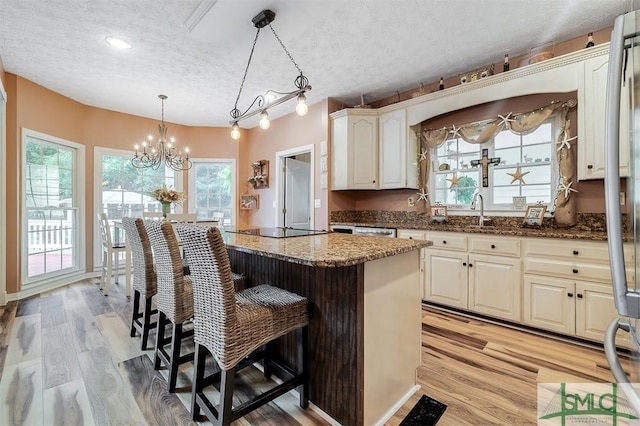 kitchen featuring pendant lighting, a textured ceiling, a center island, and dark stone counters