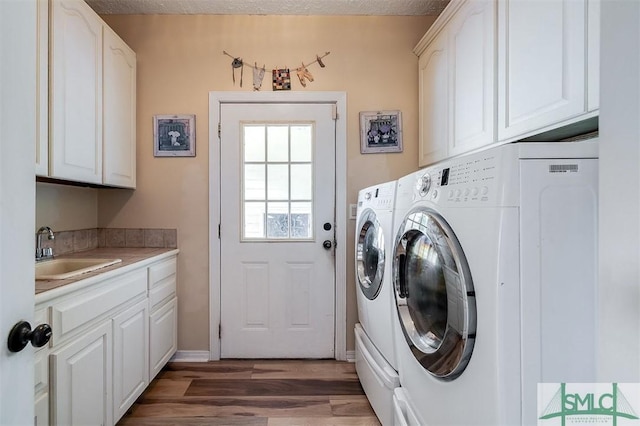 clothes washing area featuring cabinets, dark hardwood / wood-style flooring, a textured ceiling, sink, and separate washer and dryer