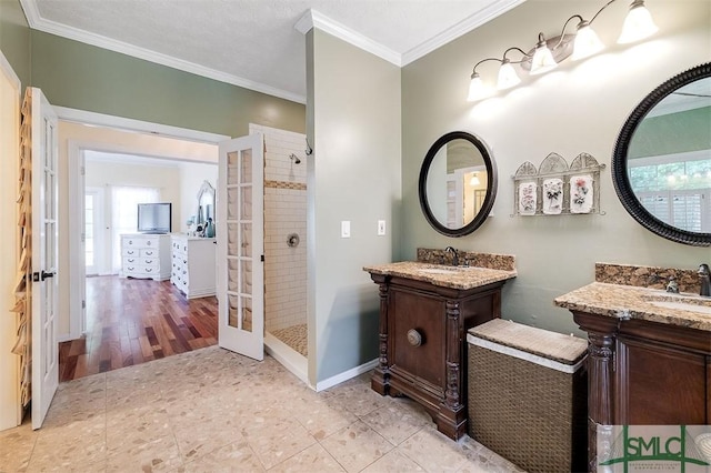 bathroom with a tile shower, crown molding, french doors, and vanity