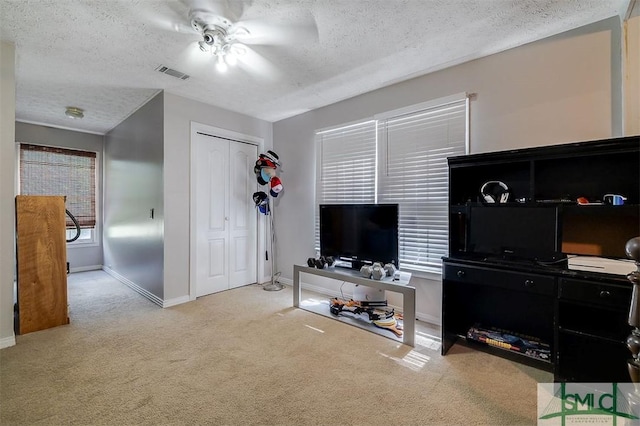 living room with a textured ceiling, light colored carpet, and ceiling fan