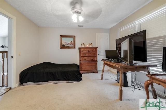 bedroom featuring ceiling fan, light carpet, and a textured ceiling