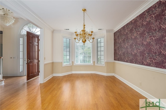 interior space with hardwood / wood-style floors, plenty of natural light, ornamental molding, and a notable chandelier