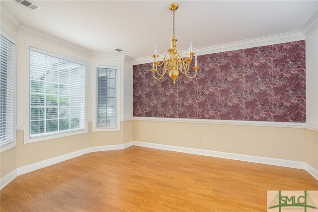 unfurnished dining area featuring crown molding, hardwood / wood-style floors, and a notable chandelier