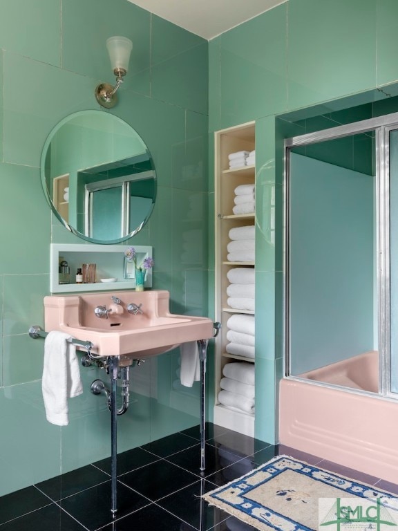 bathroom with tile floors, sink, and combined bath / shower with glass door