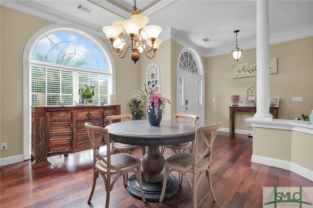 dining area featuring decorative columns, crown molding, dark wood-type flooring, and a notable chandelier