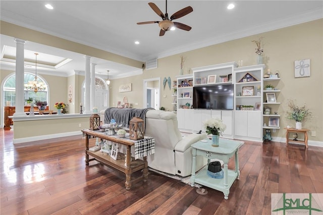 living room featuring dark wood-type flooring, ornamental molding, decorative columns, and ceiling fan with notable chandelier