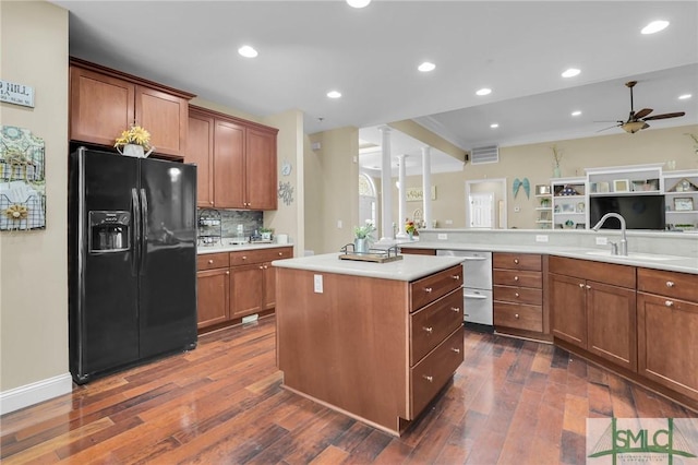 kitchen featuring dark hardwood / wood-style floors, a kitchen island, kitchen peninsula, and black fridge