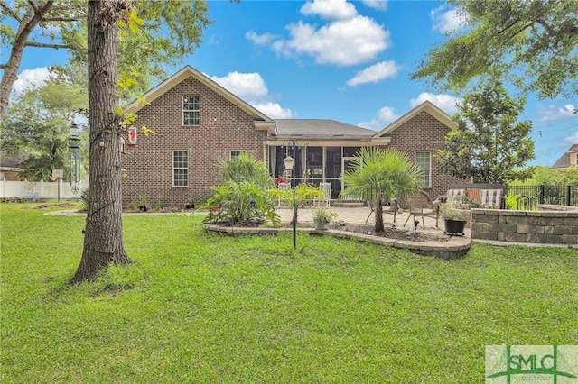 rear view of house with a sunroom, a patio, and a lawn