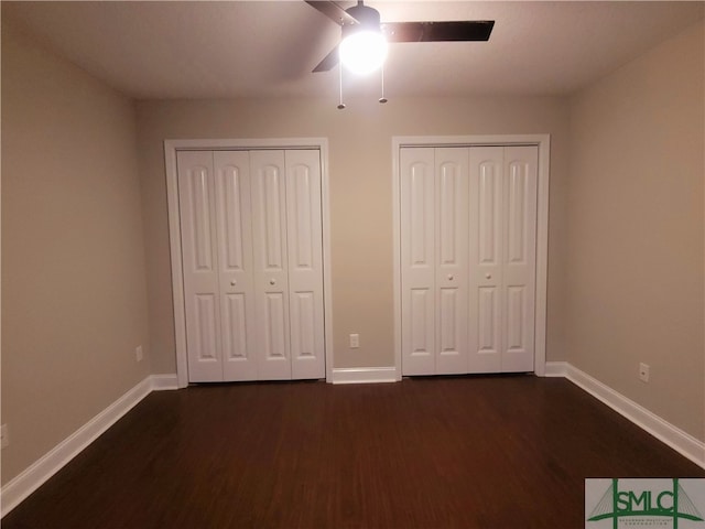 unfurnished bedroom with multiple closets, ceiling fan, and dark wood-type flooring