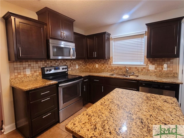 kitchen with sink, light stone countertops, decorative backsplash, and stainless steel appliances