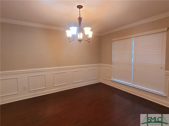 empty room featuring dark hardwood / wood-style flooring, crown molding, and a chandelier