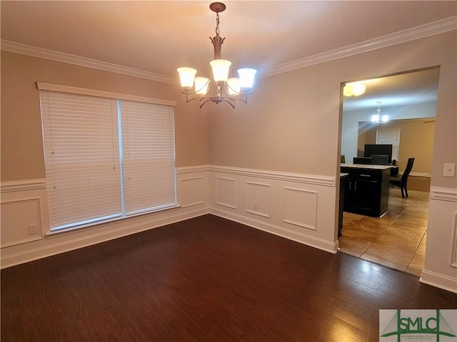 unfurnished room with wood-type flooring, ornamental molding, and an inviting chandelier