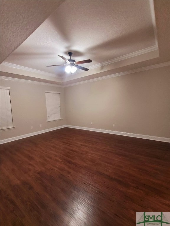 empty room with dark hardwood / wood-style floors, ceiling fan, and a raised ceiling