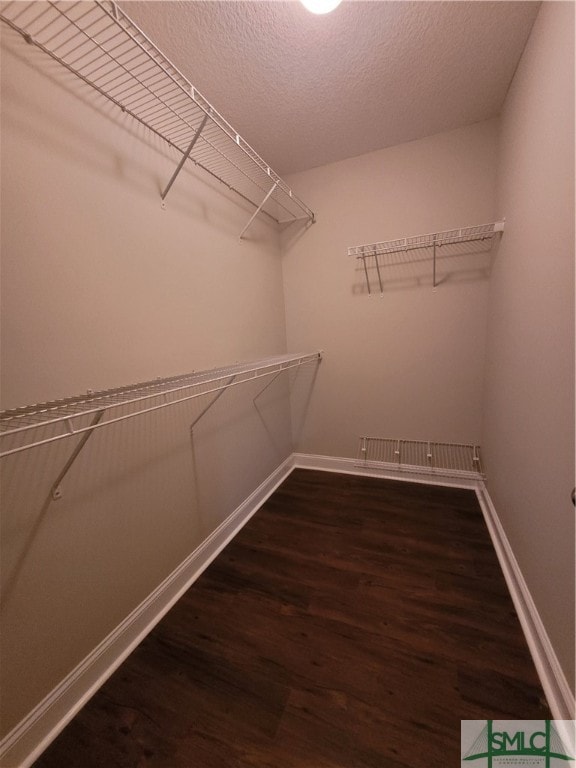 walk in closet with dark wood-type flooring