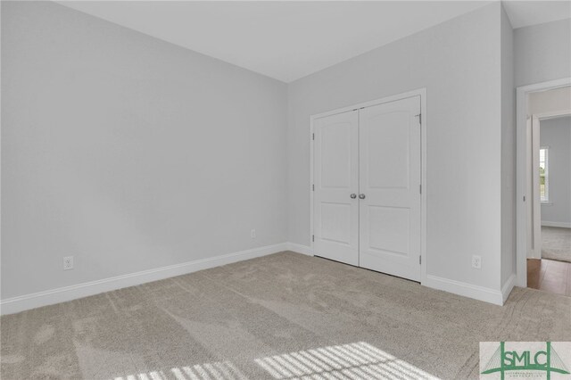 unfurnished bedroom with light carpet and a closet