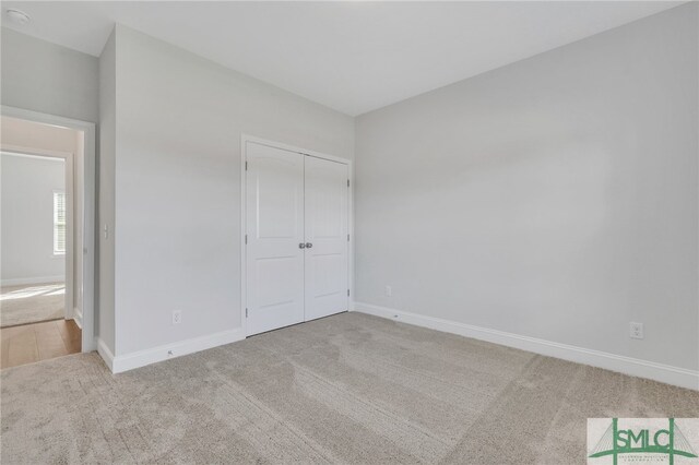 unfurnished bedroom featuring a closet and light carpet