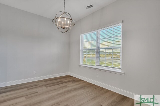 empty room featuring an inviting chandelier and light wood-type flooring