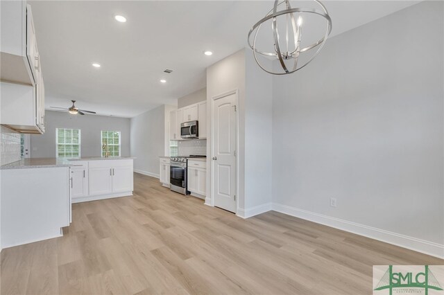 kitchen featuring white cabinetry, appliances with stainless steel finishes, decorative light fixtures, kitchen peninsula, and light hardwood / wood-style flooring