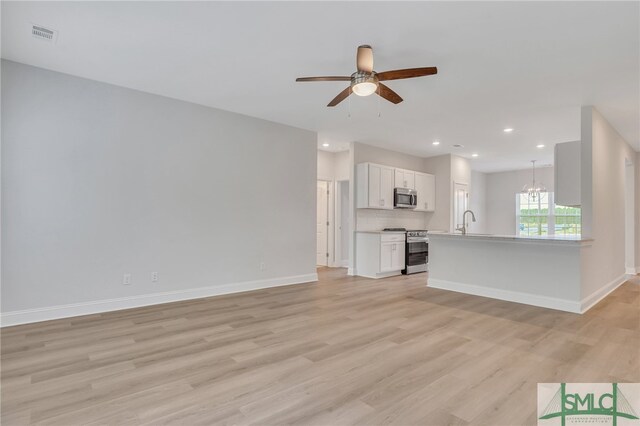 unfurnished living room with ceiling fan with notable chandelier, light hardwood / wood-style floors, and sink