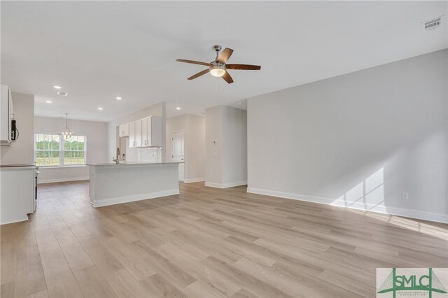 unfurnished living room featuring light hardwood / wood-style floors and ceiling fan with notable chandelier