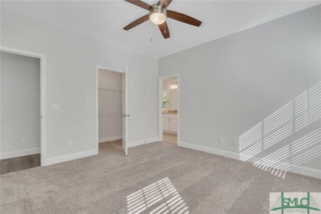 unfurnished bedroom with ceiling fan, a spacious closet, light colored carpet, connected bathroom, and a closet