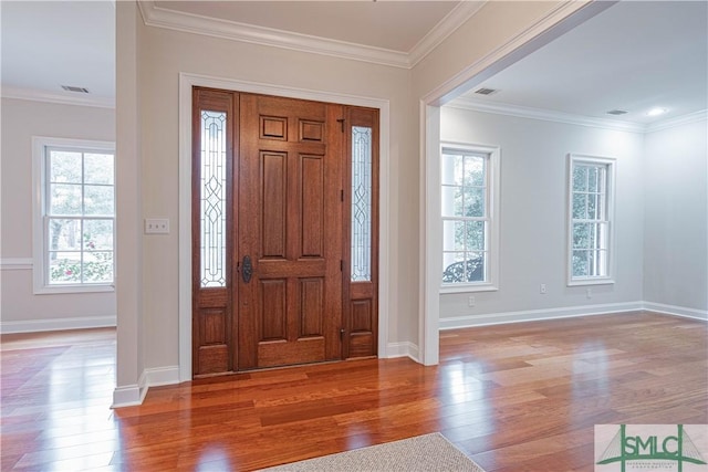 entrance foyer with hardwood / wood-style floors, a wealth of natural light, and crown molding