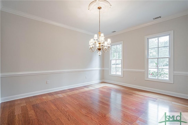 spare room with hardwood / wood-style flooring, ornamental molding, and a notable chandelier