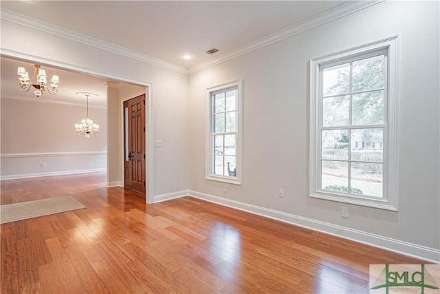 unfurnished room with a chandelier, hardwood / wood-style floors, a wealth of natural light, and crown molding