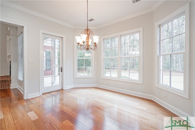 unfurnished dining area featuring a wealth of natural light, a chandelier, light wood-type flooring, and ornamental molding