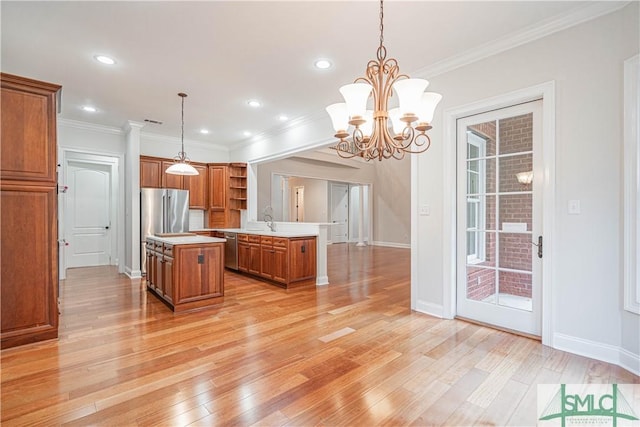 kitchen featuring stainless steel appliances, crown molding, pendant lighting, a notable chandelier, and a kitchen island