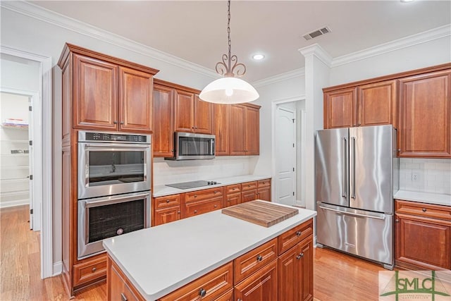 kitchen featuring appliances with stainless steel finishes, decorative light fixtures, decorative backsplash, a kitchen island, and ornamental molding