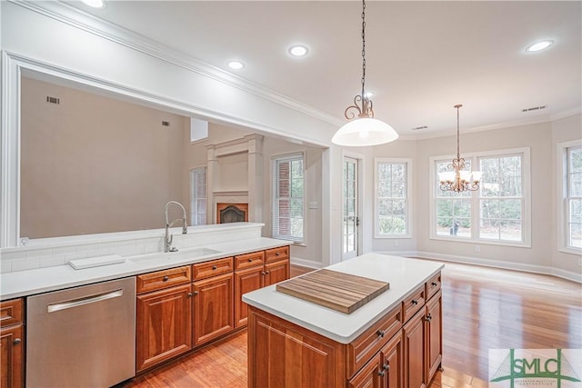 kitchen featuring a center island, sink, hanging light fixtures, stainless steel dishwasher, and a chandelier