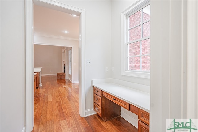 hallway featuring light wood-type flooring and crown molding