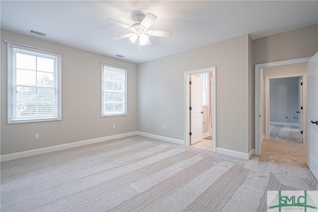 unfurnished bedroom featuring ceiling fan, light carpet, and ensuite bath