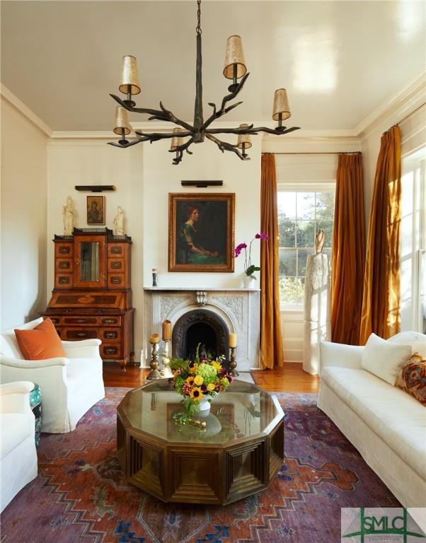 living area with dark wood-type flooring, a notable chandelier, and ornamental molding