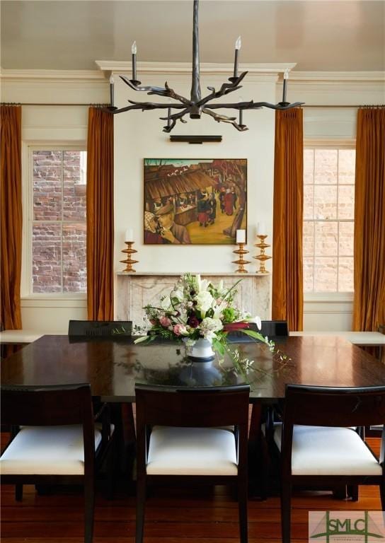 dining area featuring wood-type flooring, ornamental molding, and a notable chandelier