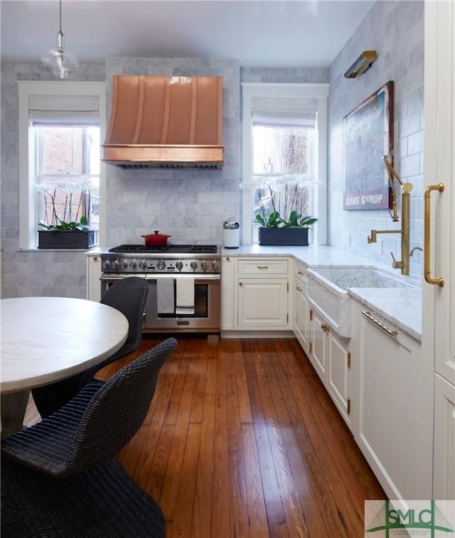 kitchen with double oven range, white cabinets, hanging light fixtures, light stone counters, and custom range hood