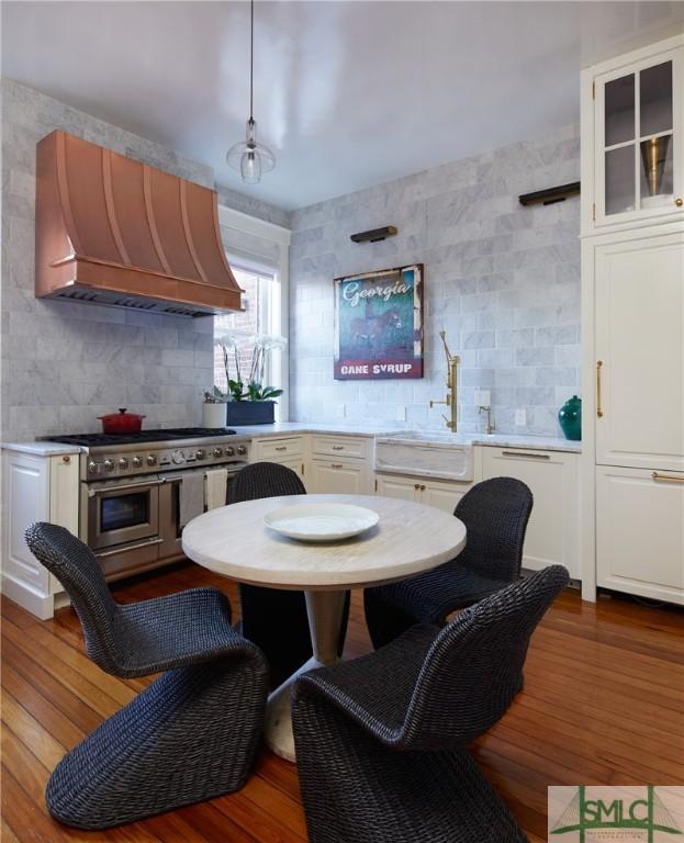 kitchen with premium range hood, white cabinets, and range with two ovens