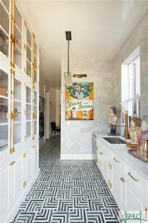 kitchen with sink, stainless steel dishwasher, light stone countertops, decorative light fixtures, and white cabinetry