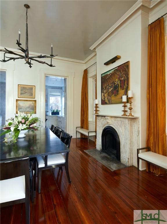 dining area featuring hardwood / wood-style floors, crown molding, a high end fireplace, and a chandelier