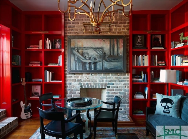 dining room featuring a notable chandelier, wood-type flooring, and a brick fireplace