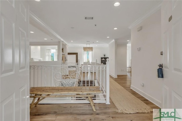 hall with a chandelier, ornamental molding, and light hardwood / wood-style flooring