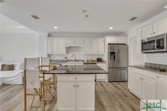 kitchen with stainless steel appliances, white cabinets, crown molding, light hardwood / wood-style flooring, and sink