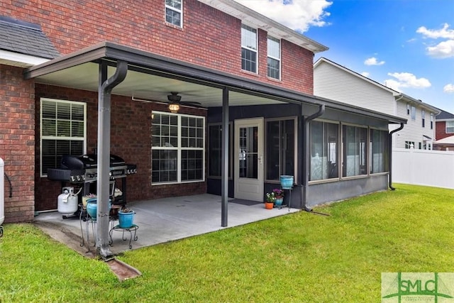 rear view of house with a patio area, ceiling fan, a sunroom, and a yard